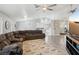 Bright living room with wood plank flooring, a ceiling fan, a large sectional sofa, and an adjacent kitchen at 7621 Gosport Ave, Las Vegas, NV 89131