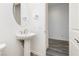 Stylish powder room featuring a pedestal sink, oval mirror, and wood-look flooring at 856 Watford Pl, Henderson, NV 89011