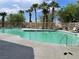 Community swimming pool and deck area with lounge chairs, manicured landscaping, and palm trees at 8680 Horizon Wind Ave # 101, Las Vegas, NV 89178