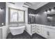 A modern bathroom featuring a soaking tub, a window, marble countertops, two sinks, and stylish fixtures at 8864 La Manga Ave, Las Vegas, NV 89147