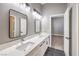 Bathroom with double sink vanity, black hexagon flooring, framed mirrors and lighting fixtures at 8864 La Manga Ave, Las Vegas, NV 89147