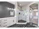Modern bathroom with a marble tiled shower, quartz countertop, gray accent wall and black hexagon tile flooring at 8864 La Manga Ave, Las Vegas, NV 89147