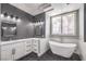 A modern bathroom featuring a soaking tub, a window, marble countertops, two sinks, and stylish fixtures at 8864 La Manga Ave, Las Vegas, NV 89147