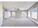 The main bedroom is an empty space with multiple windows, carpet flooring and a ceiling fan at 8864 La Manga Ave, Las Vegas, NV 89147