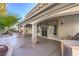 Exterior view of the covered patio with concrete flooring, landscaping with palm trees and an outdoor grill at 8864 La Manga Ave, Las Vegas, NV 89147
