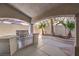 Covered patio features a stainless steel grill, concrete flooring and landscaping with palm trees at 8864 La Manga Ave, Las Vegas, NV 89147