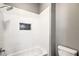 Shower and bathtub combination with white wall tiles, hexagon tile niche, chrome shower head, and toilet at 8864 La Manga Ave, Las Vegas, NV 89147