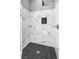 Close up view of a marble tiled shower with black hexagon tile flooring and niche with chrome shower head at 8864 La Manga Ave, Las Vegas, NV 89147