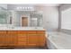 Bathroom featuring dual sinks, a large mirror, a bathtub, and oak cabinets at 9071 Mount Wilson St, Las Vegas, NV 89113