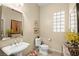 Powder room featuring a pedestal sink, toilet, and decorative accents with an art-deco mirror at 9172 Tudor Park Pl, Las Vegas, NV 89145