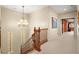 Carpeted hallway with wood railing overlooking the stairs and natural light through glass block windows at 9172 Tudor Park Pl, Las Vegas, NV 89145