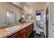 Bright bathroom boasts dual sinks, a tiled countertop, dark wood cabinetry, and access to the shower and bedroom at 949 Via Stellato St, Henderson, NV 89011