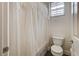 Bathroom featuring a toilet, shower/tub with white tile and lace curtain, and a window for natural light at 949 Via Stellato St, Henderson, NV 89011