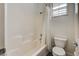 Another angle of the bathroom displaying a shower/tub, white tile, lace curtain, a toilet, and a window at 949 Via Stellato St, Henderson, NV 89011