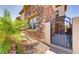 View of the side of the home featuring stone accents, an iron gate, and lush landscaping at 949 Via Stellato St, Henderson, NV 89011