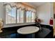 Spa like bathroom with large windows, black granite countertops, and an oval soaking tub at 949 Via Stellato St, Henderson, NV 89011