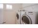 Bright laundry room with white washer and dryer, overhead shelf, and shuttered window at 9617 Fast Elk St, Las Vegas, NV 89143