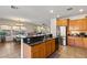 Open kitchen with island, wood cabinets, stainless steel refrigerator, and tile flooring at 10133 Longoria St, Las Vegas, NV 89178