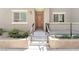 Front porch with steps, metal railing, neutral-colored stucco, and tidy landscaping at 12367 Indigo Montage Rd # 3, Las Vegas, NV 89183