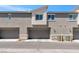 Exterior view of a townhome featuring garages and beige stucco under a bright blue sky at 12367 Indigo Montage Rd # 3, Las Vegas, NV 89183