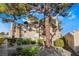 Condominium exterior showcasing mature trees, stucco siding, and lush green landscaping at 2251 Wigwam Pkwy # 923, Henderson, NV 89074