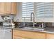 Close-up of kitchen sink with black granite counters, stainless steel appliances, and wooden cabinets at 2445 Rue Royale, Henderson, NV 89044