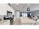 Open-concept kitchen with a large island, white cabinets, stainless steel appliances, and an adjacent living area at 2539 Ballatore St, Henderson, NV 89044