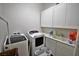 Bright laundry room with white cabinets, front load washer and dryer, and utility sink at 2539 Ballatore St, Henderson, NV 89044