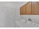 Laundry room with white appliances, wood cabinets, and a white door at 3525 Hammock St, Las Vegas, NV 89147