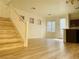 Sun-filled living room with wood-look flooring, staircase, and access to the kitchen with modern finishes at 3525 Hammock St, Las Vegas, NV 89147