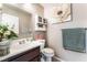 Bathroom featuring a single sink vanity, mirror, toilet, flower decorations, and wall art at 3744 Archer St, Las Vegas, NV 89108