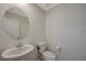 Bathroom with a pedestal sink, round mirror, and a standard toilet with neutral wall paint at 5691 Tinar St, Las Vegas, NV 89113