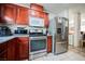 Modern kitchen with stainless steel appliances, cherry wood cabinets, and a tile floor at 653 Del Giorno St, Las Vegas, NV 89138