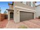Close-up of a two-story home featuring a brown two-car garage, green door, and well-manicured desert landscaping at 6619 Frosted Harvest Ave, Las Vegas, NV 89108