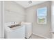 A dedicated laundry room featuring a washer, dryer, and shelving for storage, located inside the home at 6619 Frosted Harvest Ave, Las Vegas, NV 89108