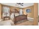 This bedroom features a decorative wood-trimmed bed, ceiling fan, bedside table, and warm-toned walls at 7436 Oak Grove Ave, Las Vegas, NV 89117