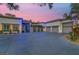 Stately home exterior illuminated with accent lighting, featuring a multi-car garage and large driveway, under a vibrant twilight sky at 7436 Oak Grove Ave, Las Vegas, NV 89117