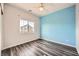 Bedroom featuring a light blue accent wall, hardwood floors, and a window overlooking the neighborhood at 7745 Tyrell Peaks St, Las Vegas, NV 89139