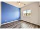 Bedroom featuring a dark blue accent wall, hardwood floors, and a window overlooking the neighborhood at 7745 Tyrell Peaks St, Las Vegas, NV 89139
