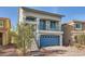 Two-story home featuring a blue garage door, a balcony, and a charming front yard at 7745 Tyrell Peaks St, Las Vegas, NV 89139