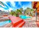 Stunning backyard pool featuring an orange bridge, rock features, and mature palm tree landscaping at 7748 Firethorn Ln, Las Vegas, NV 89123