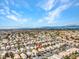 High aerial shot displaying a community of uniform homes nestled beneath a vast, partly cloudy blue sky at 8005 Dover Shores Ave, Las Vegas, NV 89128