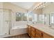 Bright bathroom offers double sinks, wood cabinets, a glass shower, a soaking tub, and large window at 8005 Dover Shores Ave, Las Vegas, NV 89128