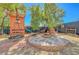 Backyard featuring a playhouse with a swing, an outdoor seating area with a fire pit and trees at 8633 Radiant Ruby Ave, Las Vegas, NV 89143