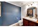 Cozy half bathroom with a wood vanity, a decorative mirror, and modern fixtures at 8633 Radiant Ruby Ave, Las Vegas, NV 89143