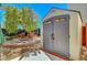 A backyard shed with wood and gray panels near a fire pit and some Adirondack chairs at 8633 Radiant Ruby Ave, Las Vegas, NV 89143