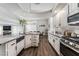 Open concept kitchen with stainless steel appliances, granite countertops, white cabinets, and wood-look flooring at 8729 Country View Ave, Las Vegas, NV 89129