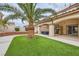 Landscaped backyard featuring artificial grass, mature palm tree, and covered patio at 9611 Trattoria St, Las Vegas, NV 89178