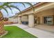 Backyard featuring artificial grass, mature palm tree, and covered patio at 9611 Trattoria St, Las Vegas, NV 89178
