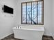 Bright bathroom with a modern soaking tub, decorative screen, and mounted television at 10062 Mountain Foothills Ave, Las Vegas, NV 89149